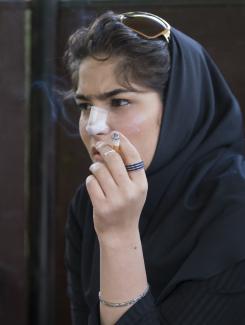 A woman smokes as she rests at a park, in central Tehran, Iran, on April 9, 2009.