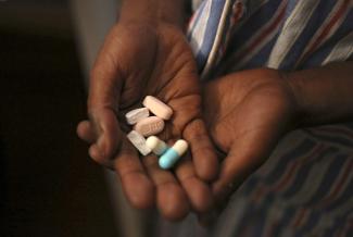 A boy holds a handful of antiretroviral pills before taking his medication at Nkosi's Haven, in Johannesburg, South Africa, on November 28, 2014.