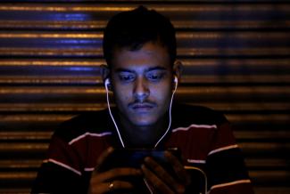 A man watches a movie on his phone, in Delhi, India, on November 16, 2016.