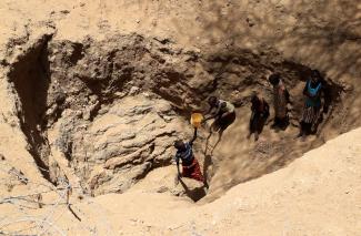 Members of the Turkana pastoralist community affected by the worsening drought due to failed rain seasons, collect water from an open well dug on a dry riverbed, Turkana, Kenya, on September 27, 2022.