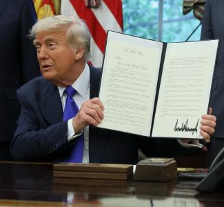 U.S. President Donald Trump shows a signed document as he signs executive orders and proclamations, in the Oval Office at the White House, in Washington, DC, on May 5, 2025.