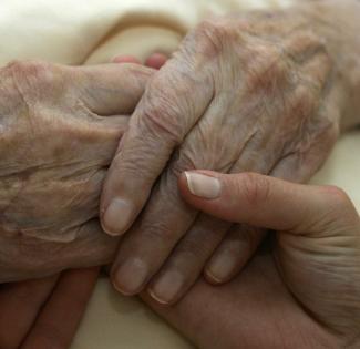 A caregiver holds the hands of an elderly woman, in Planegg, Germany, on June 19, 2007.