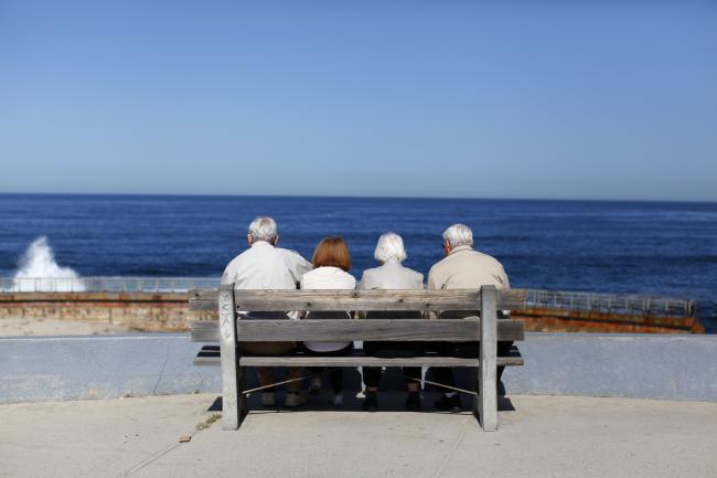 A pair of elderly couples view the ocean and waves along the beach.