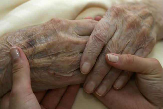 A caregiver holds the hands of an elderly woman, in Planegg, Germany, on June 19, 2007.